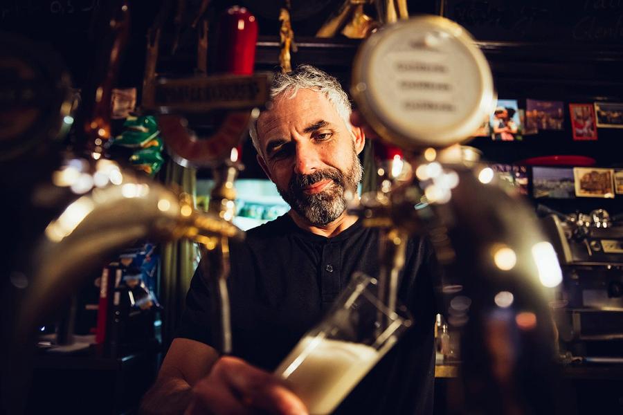Barman tapt een glas bier achter de toog